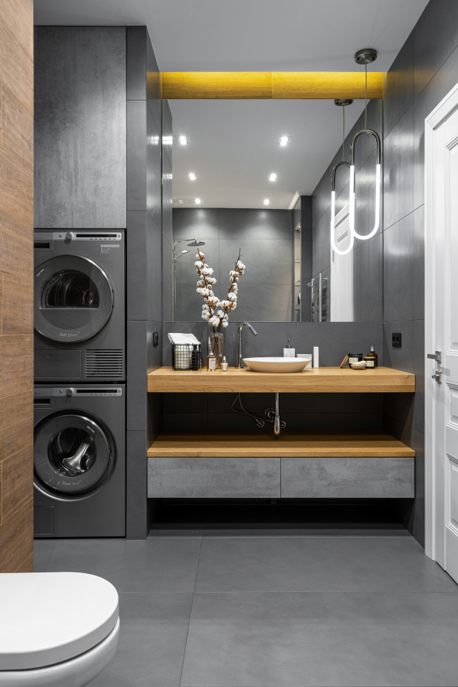 Inspiration for a mid-sized contemporary master gray tile and porcelain tile porcelain tile, gray floor and single-sink bathroom remodel in Saint Petersburg with flat-panel cabinets, medium tone wood cabinets, a wall-mount toilet, gray walls, wood countertops, a floating vanity and a vessel sink