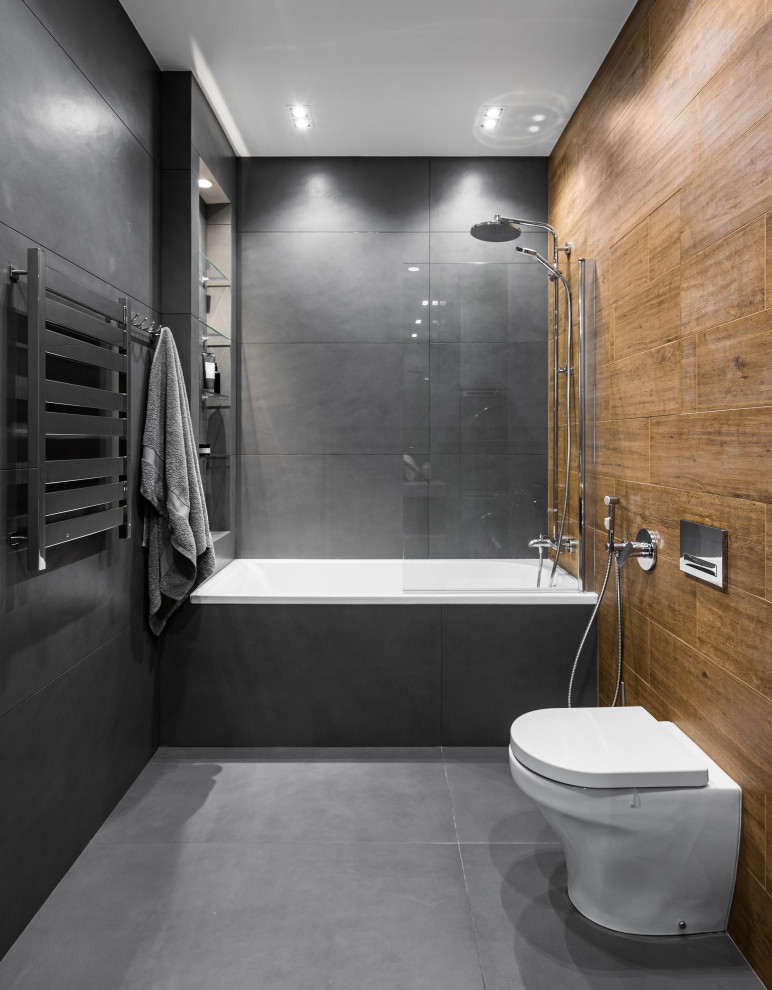 Foto på ett mellanstort funkis en-suite badrum, med släta luckor, skåp i mellenmörkt trä, ett badkar i en alkov, en dusch/badkar-kombination, en vägghängd toalettstol, grå kakel, porslinskakel, grå väggar, klinkergolv i porslin, ett nedsänkt handfat, träbänkskiva, grått golv och dusch med duschdraperi