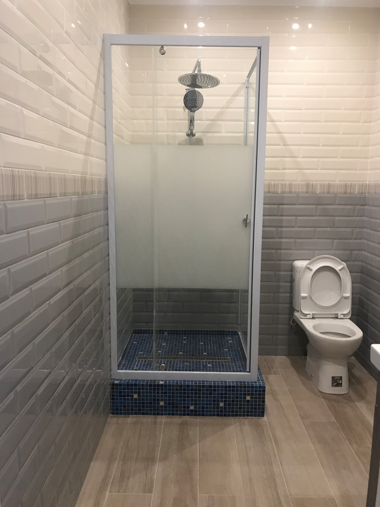 This is an example of a small scandinavian shower room bathroom in Moscow with medium wood cabinets, a corner shower, a one-piece toilet, ceramic tiles, grey walls, porcelain flooring, beige floors, a hinged door and a feature wall.