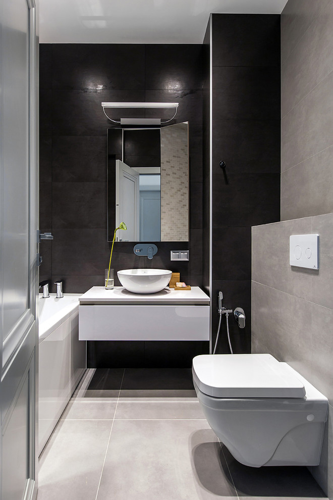 Стильный дизайн: маленькая главная ванная комната в современном стиле с плоскими фасадами, белыми фасадами, ванной в нише, инсталляцией, серой плиткой, черной плиткой, настольной раковиной и серым полом для на участке и в саду - последний тренд
