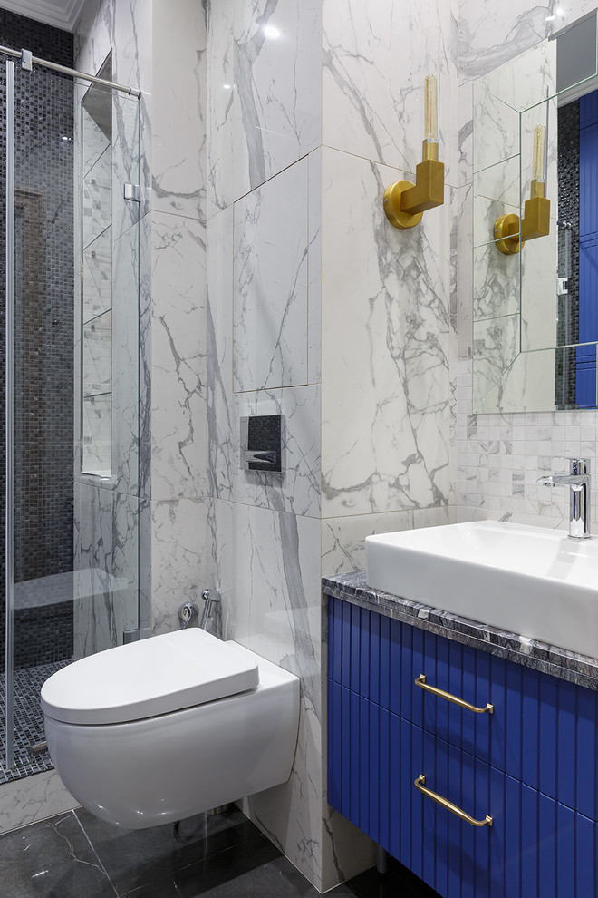 Foto de cuarto de baño tradicional renovado, de tamaño medio, con aseo y ducha, puertas de armario azules, ducha empotrada, sanitario de pared, baldosas y/o azulejos negros, baldosas y/o azulejos grises, baldosas y/o azulejos de porcelana, suelo de baldosas de porcelana, lavabo sobreencimera, encimera de cuarcita, suelo negro, ducha con puerta corredera, encimeras negras y armarios con paneles lisos