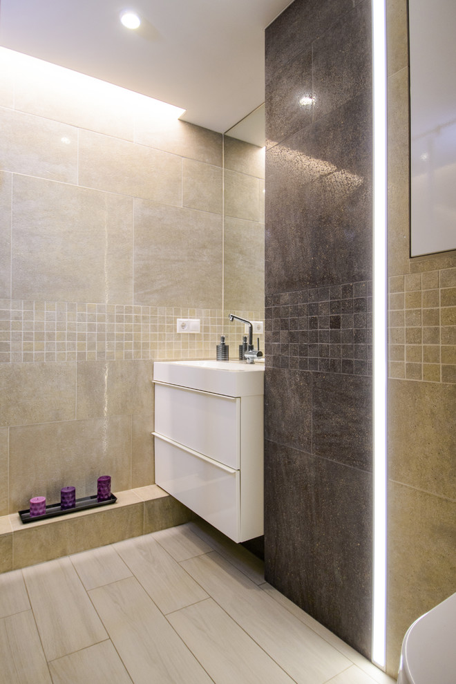 Exemple d'une salle d'eau tendance avec un placard à porte plane, des portes de placard blanches, un carrelage beige et un lavabo intégré.