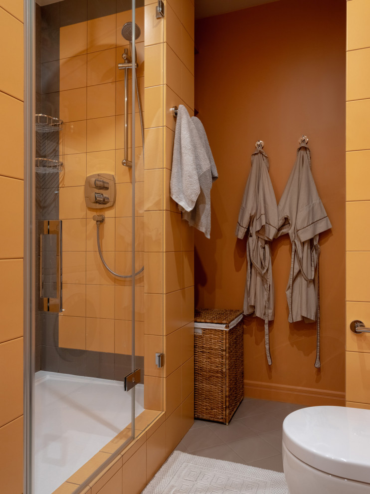 На фото: ванная комната в современном стиле с душем в нише, оранжевой плиткой, оранжевыми стенами, душевой кабиной и душем с распашными дверями с