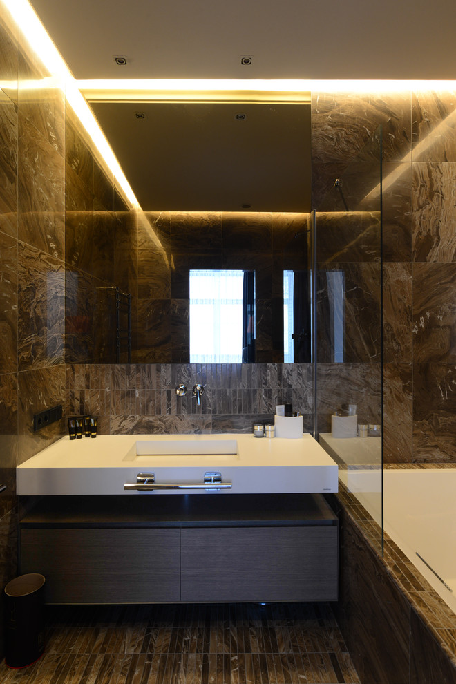 На фото: главная ванная комната среднего размера в современном стиле с плоскими фасадами, темными деревянными фасадами, душем над ванной, коричневой плиткой, керамогранитной плиткой, полом из керамогранита, монолитной раковиной, столешницей из искусственного кварца и ванной в нише с