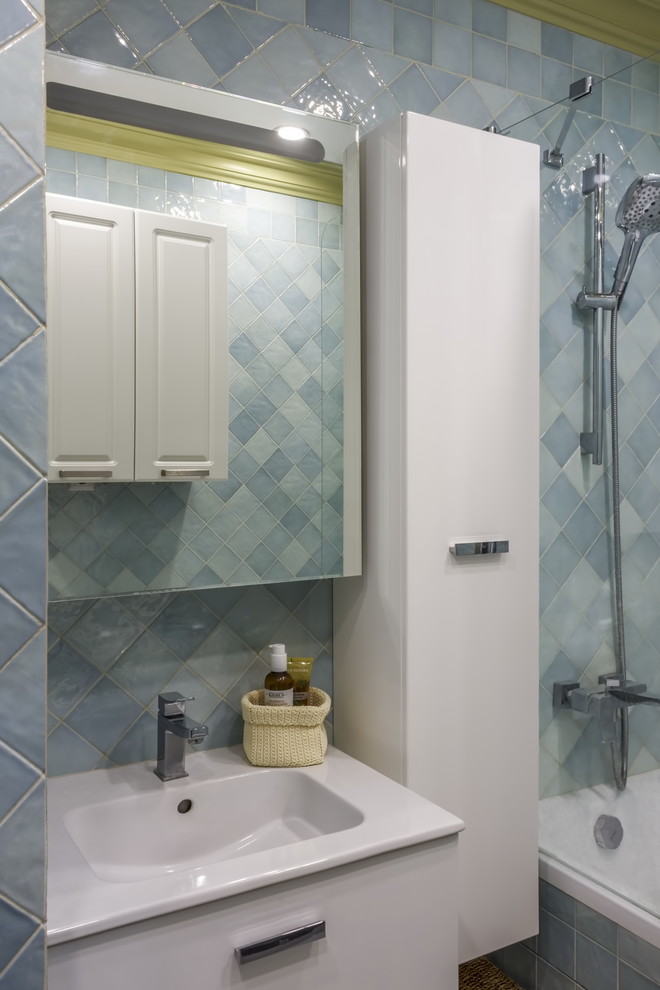 На фото: главная ванная комната с плоскими фасадами, белыми фасадами, ванной в нише, душем над ванной, синей плиткой и монолитной раковиной с