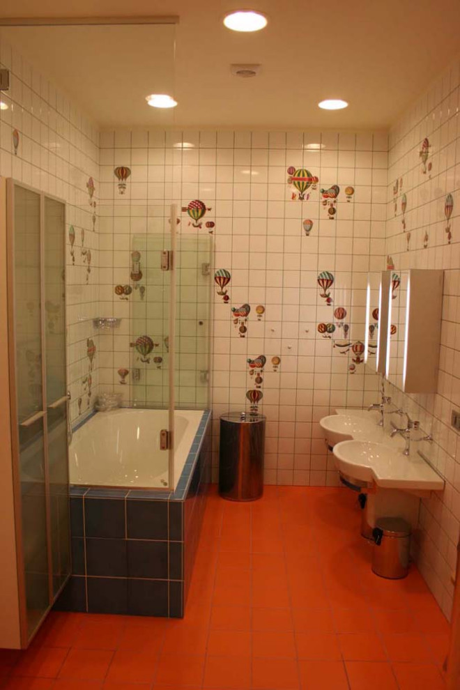 Bild på ett mellanstort funkis vit vitt badrum för barn, med luckor med glaspanel, en vägghängd toalettstol, flerfärgad kakel, keramikplattor, flerfärgade väggar, klinkergolv i keramik, ett konsol handfat, bänkskiva i akrylsten, orange golv, vita skåp, ett undermonterat badkar, en kantlös dusch och dusch med skjutdörr