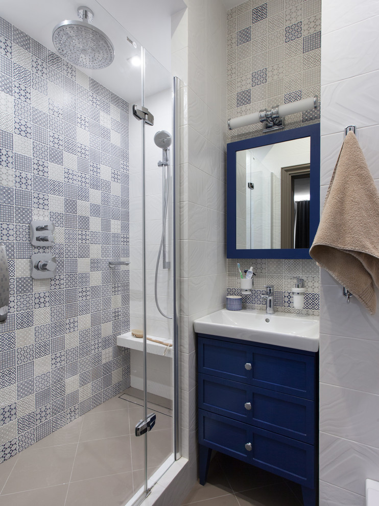 Идея дизайна: ванная комната в современном стиле с синими фасадами, синей плиткой, душевой кабиной, монолитной раковиной, душем с распашными дверями, фасадами в стиле шейкер, угловым душем, бежевым полом и белой столешницей