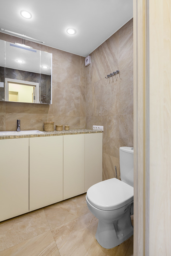 Imagen de cuarto de baño actual con armarios con paneles lisos, puertas de armario blancas, sanitario de dos piezas, baldosas y/o azulejos marrones, lavabo encastrado y suelo beige