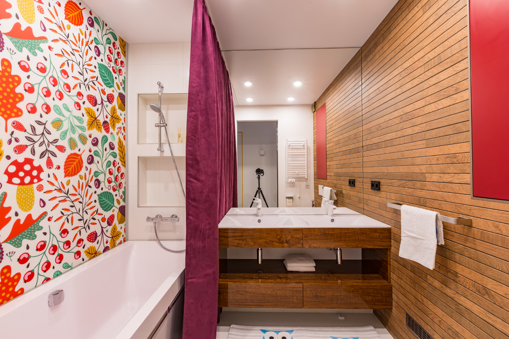 他の地域にあるコンテンポラリースタイルのおしゃれな浴室 (フラットパネル扉のキャビネット、中間色木目調キャビネット、ドロップイン型浴槽、シャワー付き浴槽	、白いタイル、マルチカラーの壁、コンソール型シンク、白い床、シャワーカーテン) の写真