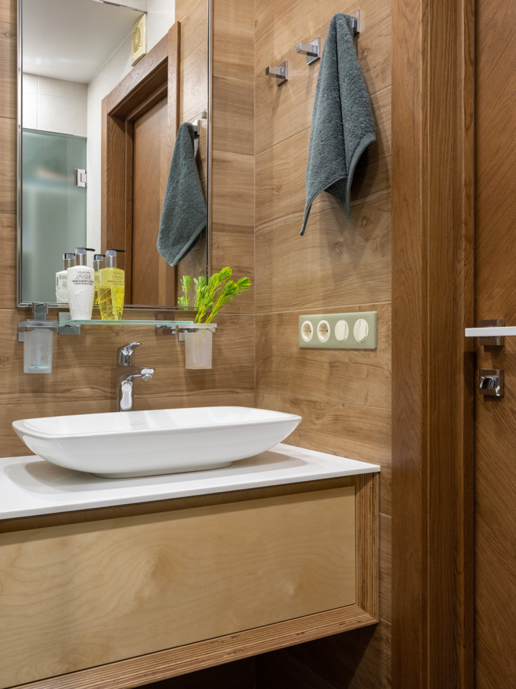 Modelo de cuarto de baño contemporáneo con armarios con paneles lisos, puertas de armario de madera oscura, lavabo sobreencimera, encimeras blancas y paredes marrones