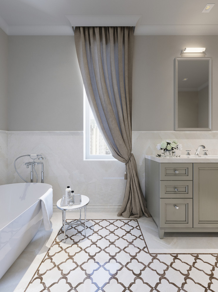 Klassisk inredning av ett mellanstort en-suite badrum, med luckor med infälld panel, grå skåp, ett fristående badkar, en vägghängd toalettstol, vit kakel, marmorkakel, grå väggar, marmorgolv, ett undermonterad handfat, marmorbänkskiva och vitt golv