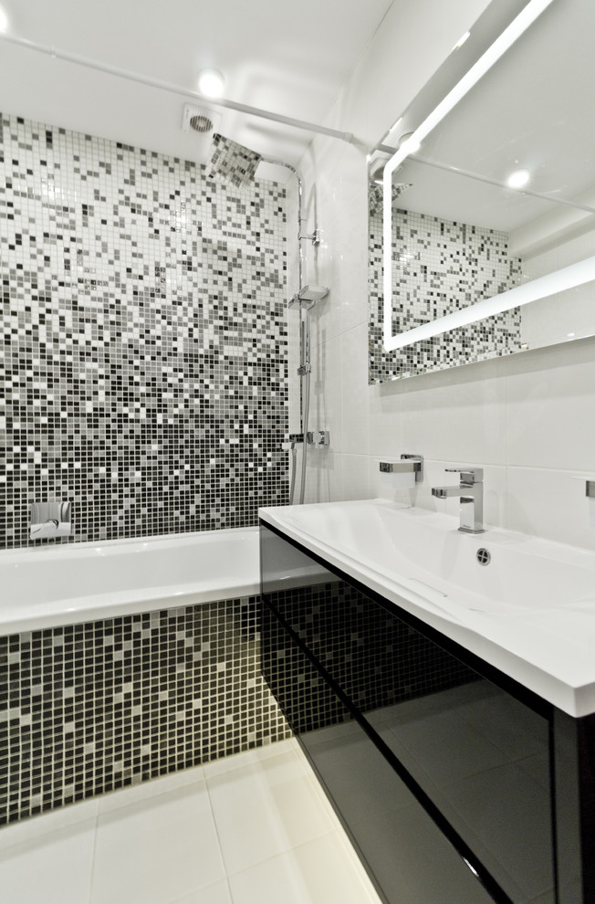 Idée de décoration pour une salle de bain design avec un placard à porte plane, des portes de placard noires, une baignoire en alcôve, un combiné douche/baignoire, un carrelage noir et blanc, mosaïque et un plan vasque.