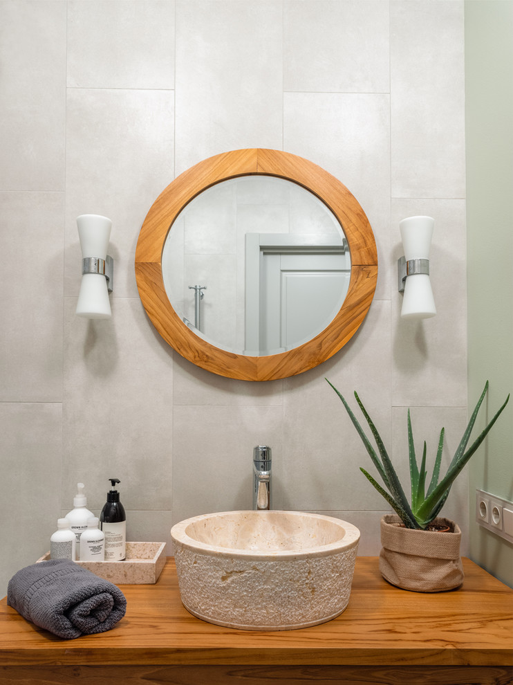 Mid-sized eclectic master gray tile and porcelain tile porcelain tile and gray floor alcove bathtub photo in Moscow with louvered cabinets, medium tone wood cabinets, a wall-mount toilet, gray walls, a drop-in sink, wood countertops and brown countertops
