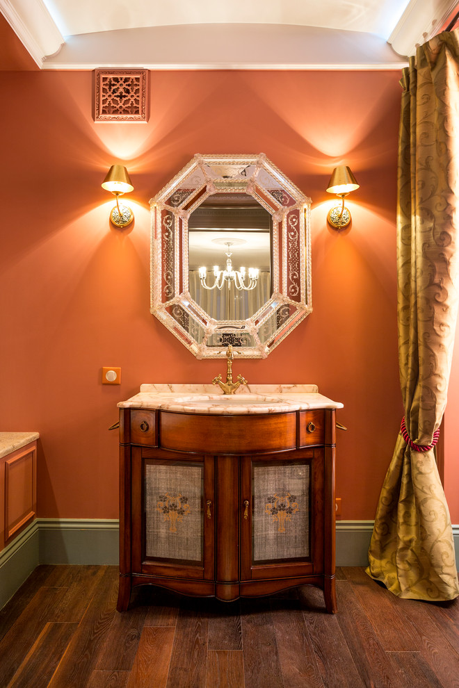 Exemple d'une salle de bain principale éclectique en bois foncé avec un mur orange, un lavabo encastré et un plan de toilette en marbre.
