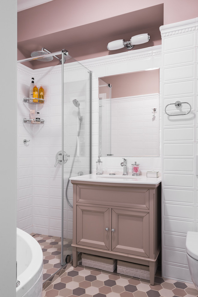 Cette image montre une salle de bain traditionnelle avec une douche d'angle, WC suspendus, un carrelage blanc, un mur rose, un lavabo encastré, une cabine de douche à porte coulissante et un placard avec porte à panneau encastré.