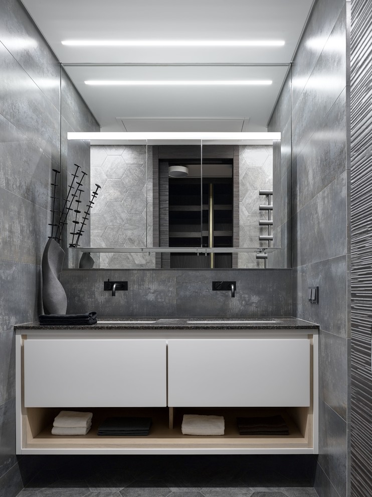 Imagen de cuarto de baño actual grande con armarios con paneles lisos, puertas de armario blancas, baldosas y/o azulejos grises y lavabo bajoencimera