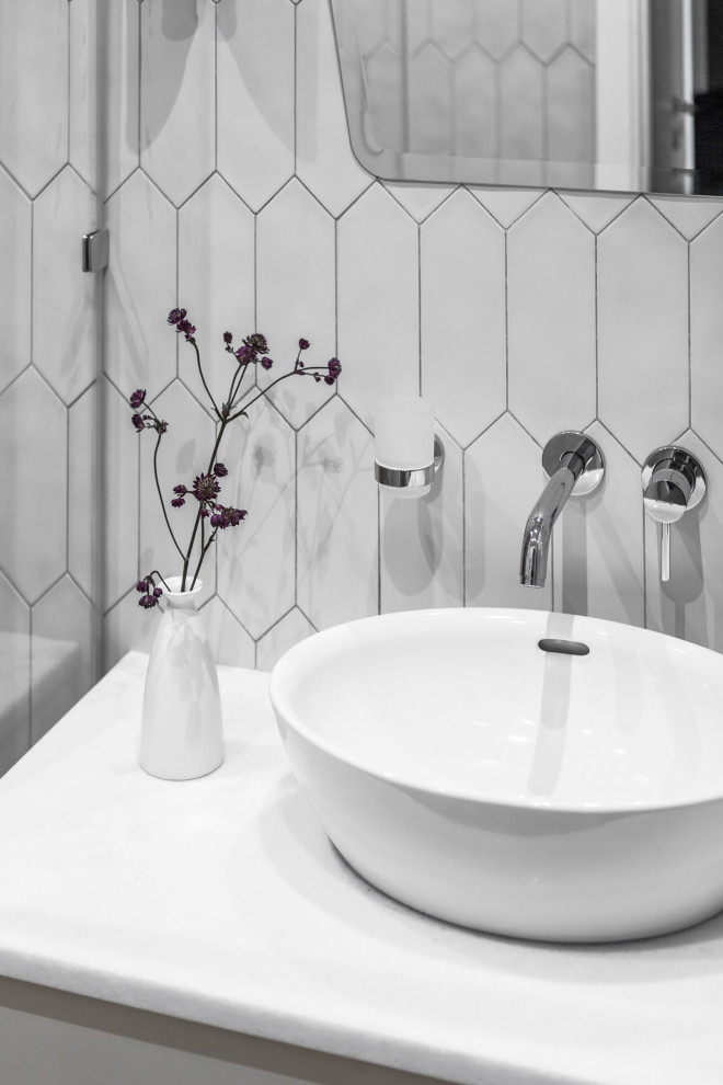 Inspiration för små skandinaviska vitt badrum med dusch, med släta luckor, vita skåp, en kantlös dusch, vit kakel, porslinskakel, vita väggar, klinkergolv i porslin, ett fristående handfat, marmorbänkskiva, brunt golv och dusch med gångjärnsdörr
