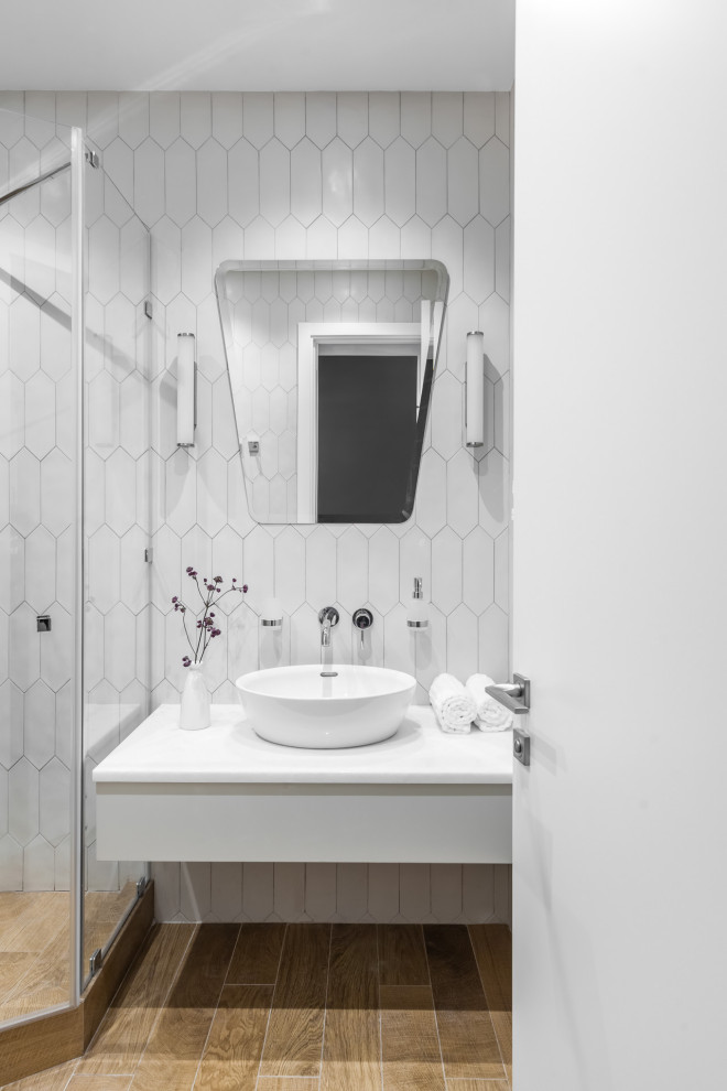 Стильный дизайн: маленькая ванная комната в скандинавском стиле с плоскими фасадами, белыми фасадами, душем без бортиков, белой плиткой, керамогранитной плиткой, белыми стенами, полом из керамогранита, душевой кабиной, настольной раковиной, мраморной столешницей, коричневым полом, душем с распашными дверями и белой столешницей для на участке и в саду - последний тренд