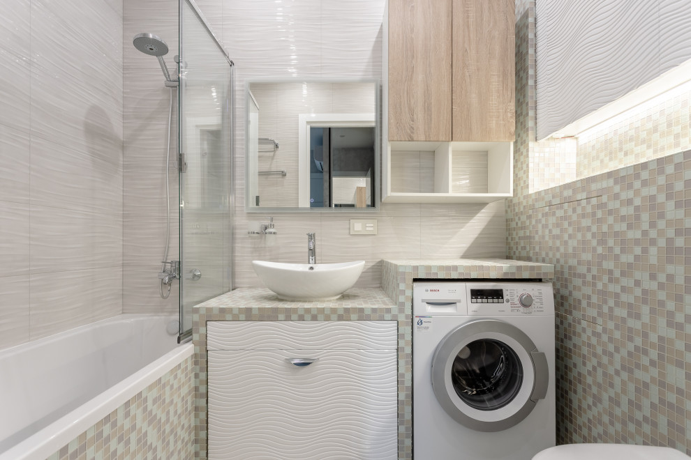 Inspiration för små moderna flerfärgat badrum med dusch, med släta luckor, vita skåp, ett badkar i en alkov, en dusch/badkar-kombination, en vägghängd toalettstol, beige kakel och ett fristående handfat