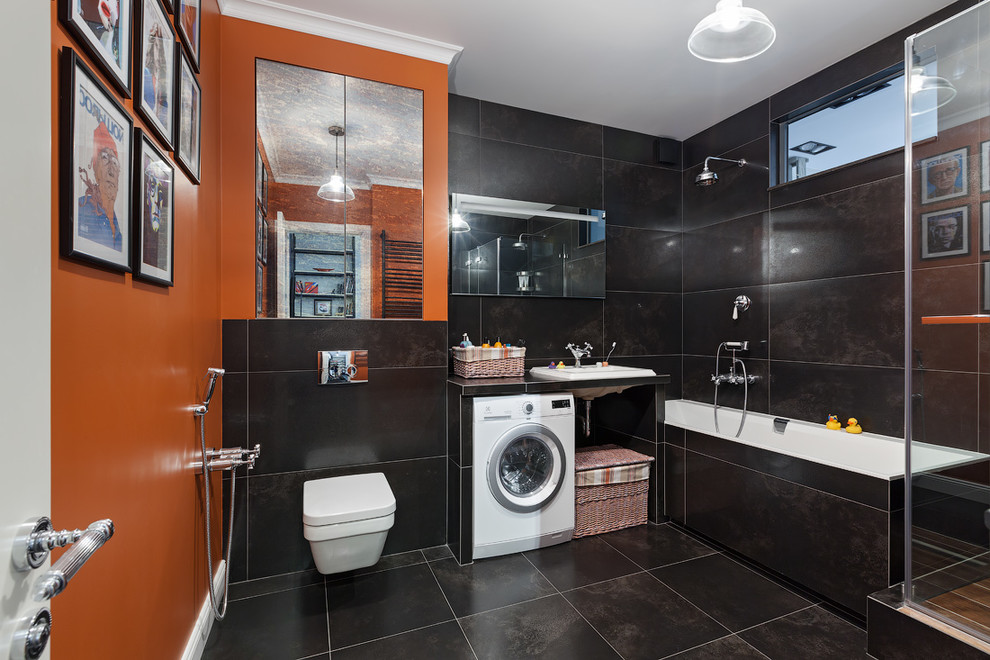 Свежая идея для дизайна: большая ванная комната в современном стиле с полновстраиваемой ванной, угловым душем, инсталляцией, черной плиткой, керамогранитной плиткой, оранжевыми стенами, полом из керамогранита, врезной раковиной, черным полом, душем с распашными дверями и черной столешницей - отличное фото интерьера