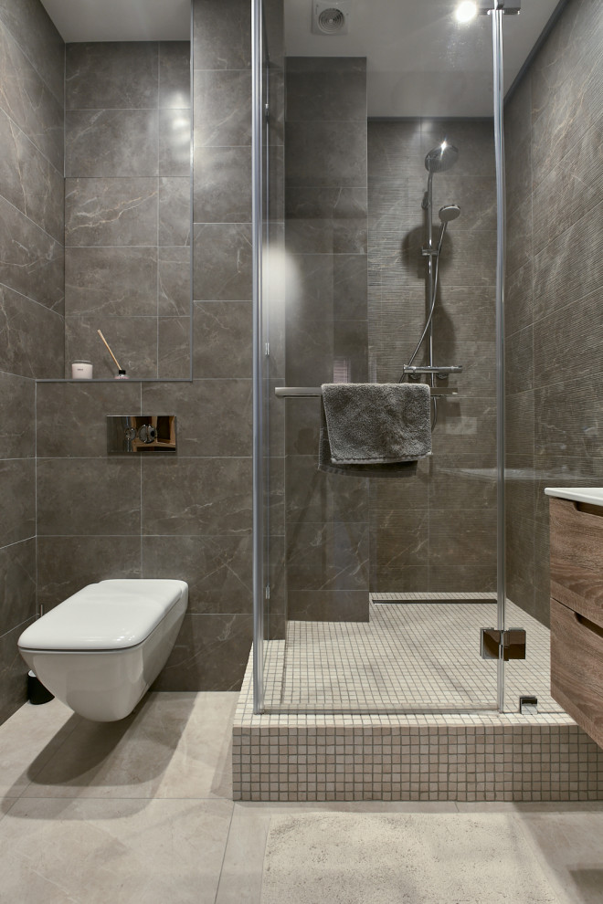 Inredning av ett industriellt mellanstort badrum med dusch, med släta luckor, skåp i mellenmörkt trä, grå kakel och ett integrerad handfat