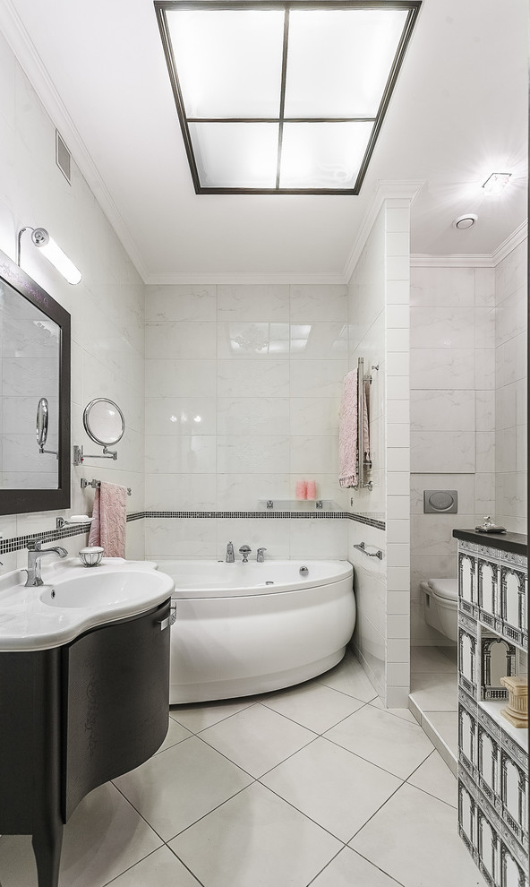 Idées déco pour une salle de bain principale contemporaine avec des portes de placard noires, une baignoire d'angle, WC suspendus, un carrelage blanc, un lavabo intégré et un sol blanc.