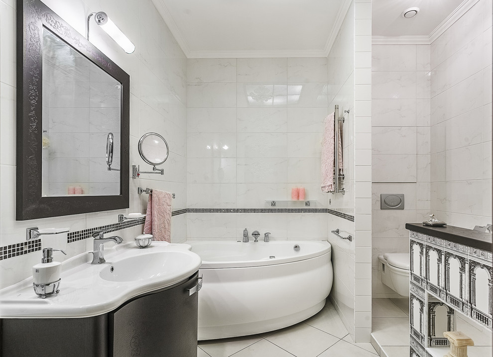 Bild på ett vintage en-suite badrum, med släta luckor, skåp i mörkt trä, ett hörnbadkar, en vägghängd toalettstol, vit kakel, keramikplattor, vita väggar, klinkergolv i keramik och ett integrerad handfat