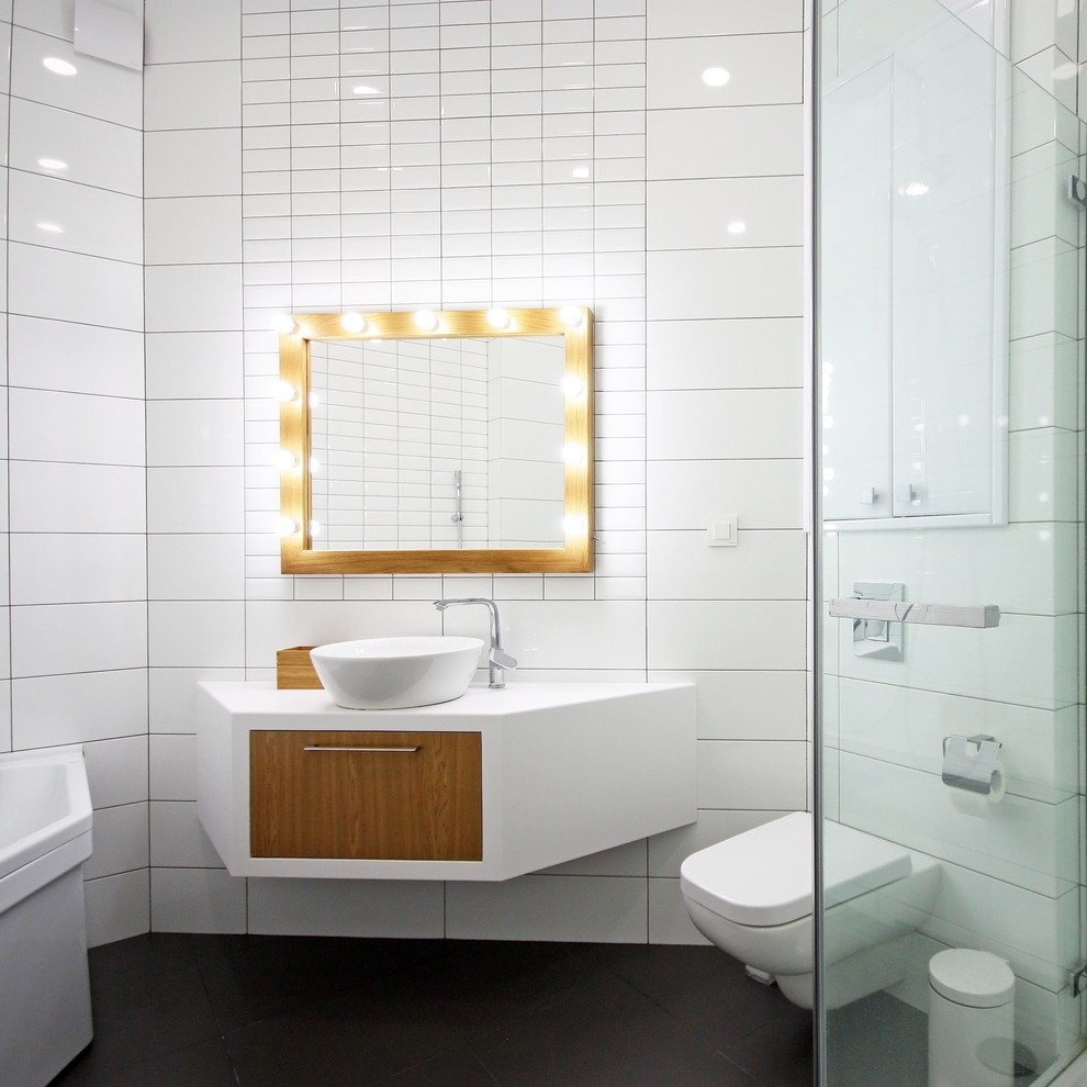 Modelo de cuarto de baño nórdico con lavabo sobreencimera, ducha esquinera, sanitario de pared y paredes blancas