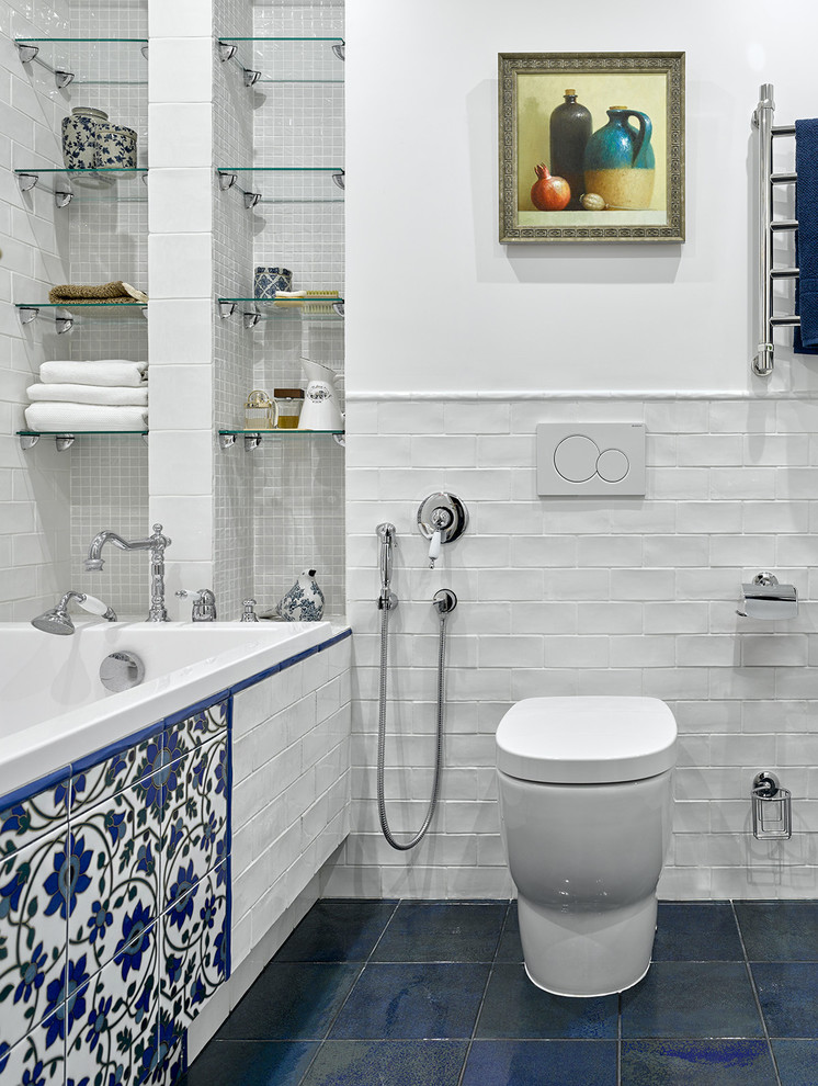 Foto di una piccola stanza da bagno boho chic con piastrelle blu, piastrelle bianche, piastrelle multicolore, pareti bianche, vasca/doccia, piastrelle in ceramica, pavimento con piastrelle in ceramica, vasca da incasso e WC sospeso