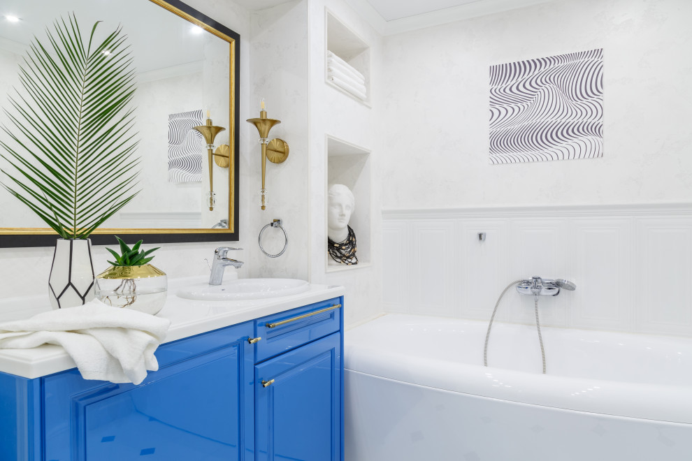Свежая идея для дизайна: ванная комната в современном стиле с фасадами с выступающей филенкой, синими фасадами, ванной в нише, белыми стенами, накладной раковиной, белой столешницей, тумбой под одну раковину и панелями на стенах - отличное фото интерьера