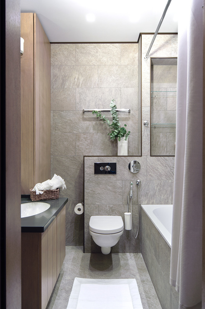 Inspiration for a small contemporary ensuite bathroom in Moscow with flat-panel cabinets, medium wood cabinets, a wall mounted toilet, grey tiles, porcelain tiles, grey walls, porcelain flooring, a submerged sink, solid surface worktops, an alcove bath, a shower/bath combination and a shower curtain.