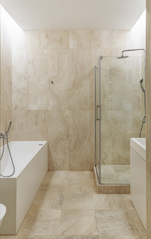 Réalisation d'une petite salle de bain design avec un placard à porte plane, des portes de placard blanches, une baignoire indépendante, une douche d'angle, un carrelage beige, des dalles de pierre, un mur beige et un sol en marbre.