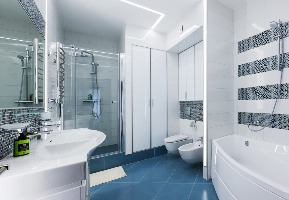 Esempio di una grande stanza da bagno padronale minimal con vasca ad angolo, doccia alcova, WC sospeso, piastrelle blu, piastrelle di vetro, pareti bianche, pavimento in gres porcellanato, lavabo rettangolare, pavimento blu e porta doccia a battente