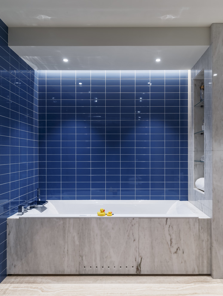 Modern inredning av ett stort badrum för barn, med blå kakel, keramikplattor, travertin golv, beiget golv och ett badkar i en alkov