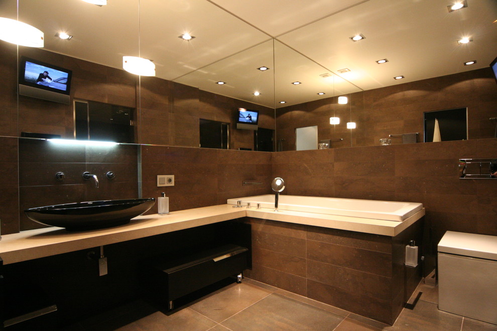 Пример оригинального дизайна: ванная комната среднего размера в современном стиле с плоскими фасадами, черными фасадами, гидромассажной ванной, душем в нише, инсталляцией, коричневой плиткой, керамогранитной плиткой, коричневыми стенами, полом из керамогранита, душевой кабиной, настольной раковиной, столешницей из искусственного камня, серым полом и душем с распашными дверями