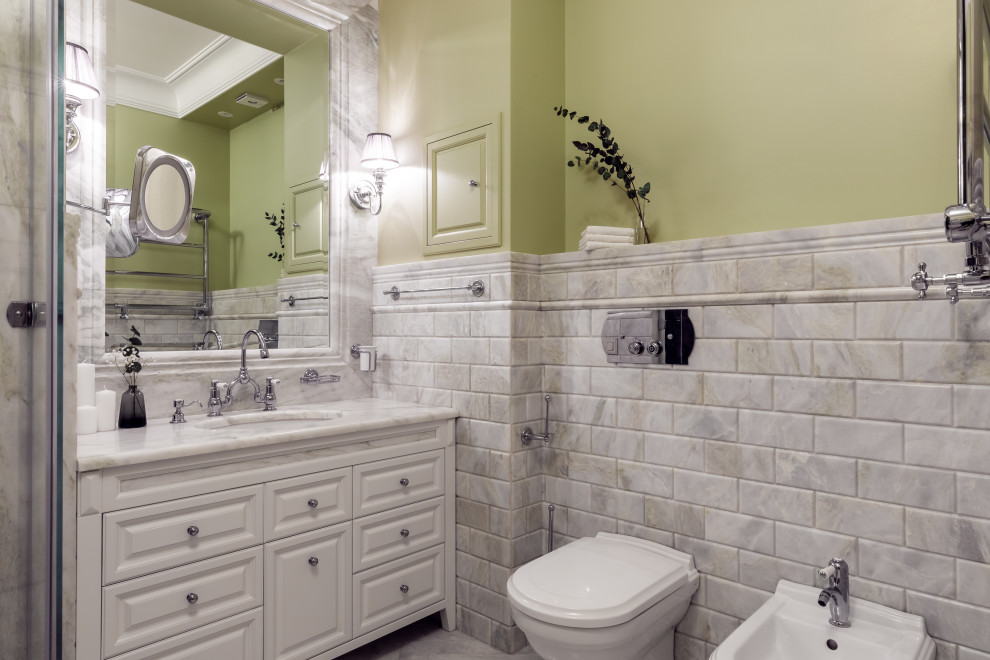 Example of a mid-sized classic master marble tile marble floor and single-sink bathroom design in Other with raised-panel cabinets, white cabinets, a wall-mount toilet, green walls, an undermount sink, marble countertops, a hinged shower door, white countertops and a freestanding vanity