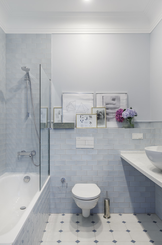 Traditional ensuite bathroom in Moscow with a shower/bath combination, a wall mounted toilet, a vessel sink, white worktops, a built-in bath, blue tiles, metro tiles, blue walls and multi-coloured floors.