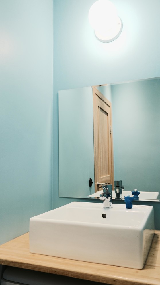 Bild på ett mellanstort funkis badrum, med ett fristående handfat, träbänkskiva och blå väggar