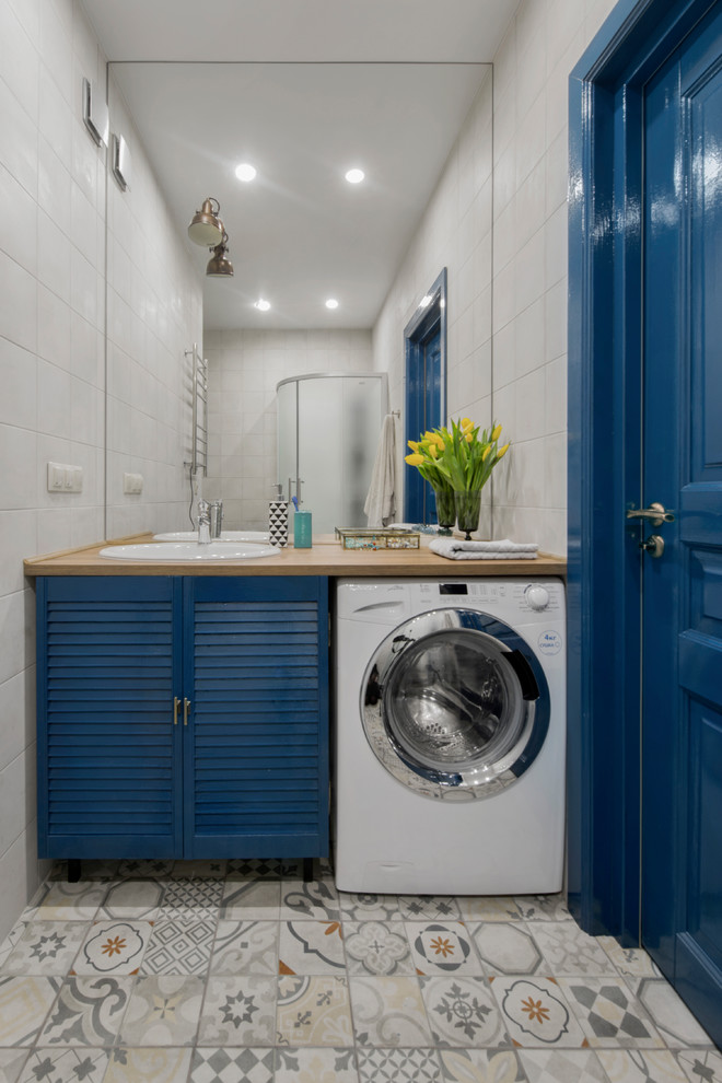 Modelo de cuarto de baño contemporáneo con armarios con puertas mallorquinas, puertas de armario azules, ducha esquinera, baldosas y/o azulejos grises, paredes grises, suelo de baldosas de cerámica y encimera de laminado