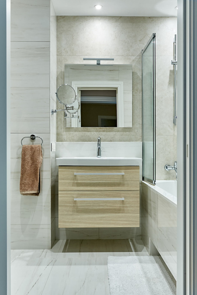 Foto di una piccola stanza da bagno contemporanea con ante lisce, ante in legno chiaro, vasca ad alcova, vasca/doccia, piastrelle beige, pareti beige, pavimento beige e top beige