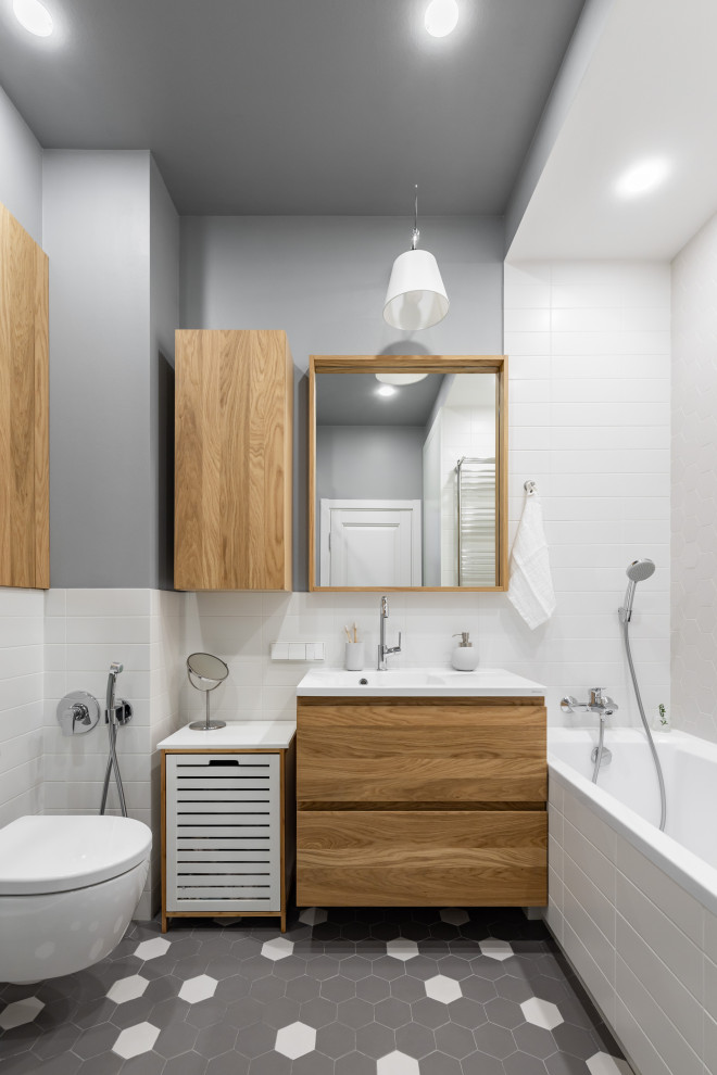 Inspiration for a medium sized scandinavian bathroom in Saint Petersburg with flat-panel cabinets, brown cabinets, an alcove bath, a corner shower, a wall mounted toilet, white tiles, ceramic tiles, grey walls, ceramic flooring, a pedestal sink, solid surface worktops, grey floors, a sliding door and white worktops.