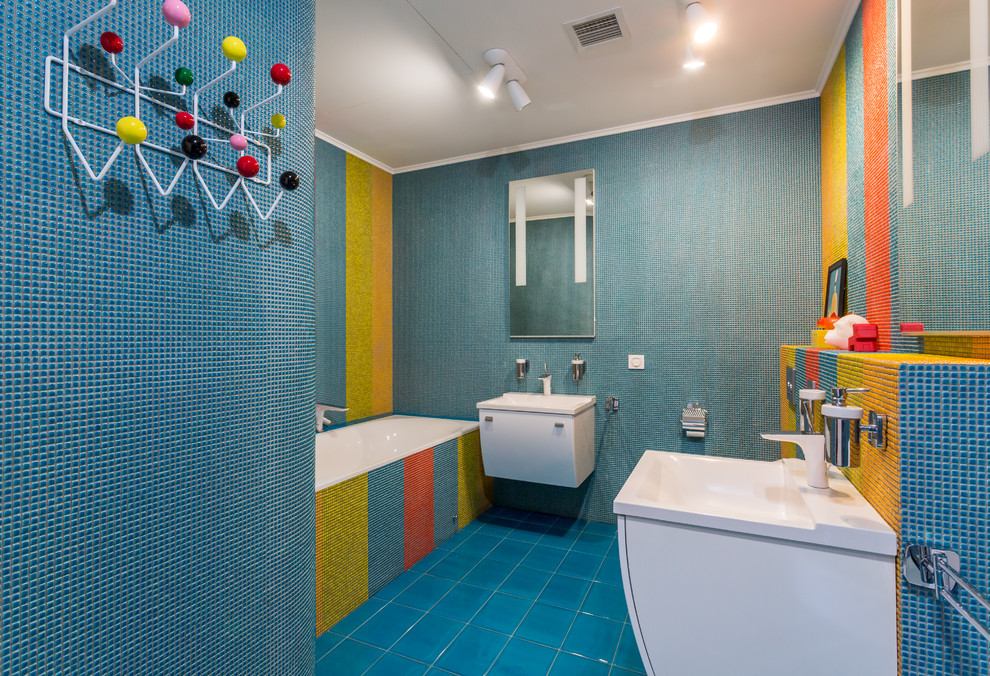 На фото: детская ванная комната среднего размера в современном стиле с ванной в нише, писсуаром, плиткой мозаикой, полом из керамической плитки, плоскими фасадами, белыми фасадами, синей плиткой, разноцветной плиткой и монолитной раковиной с