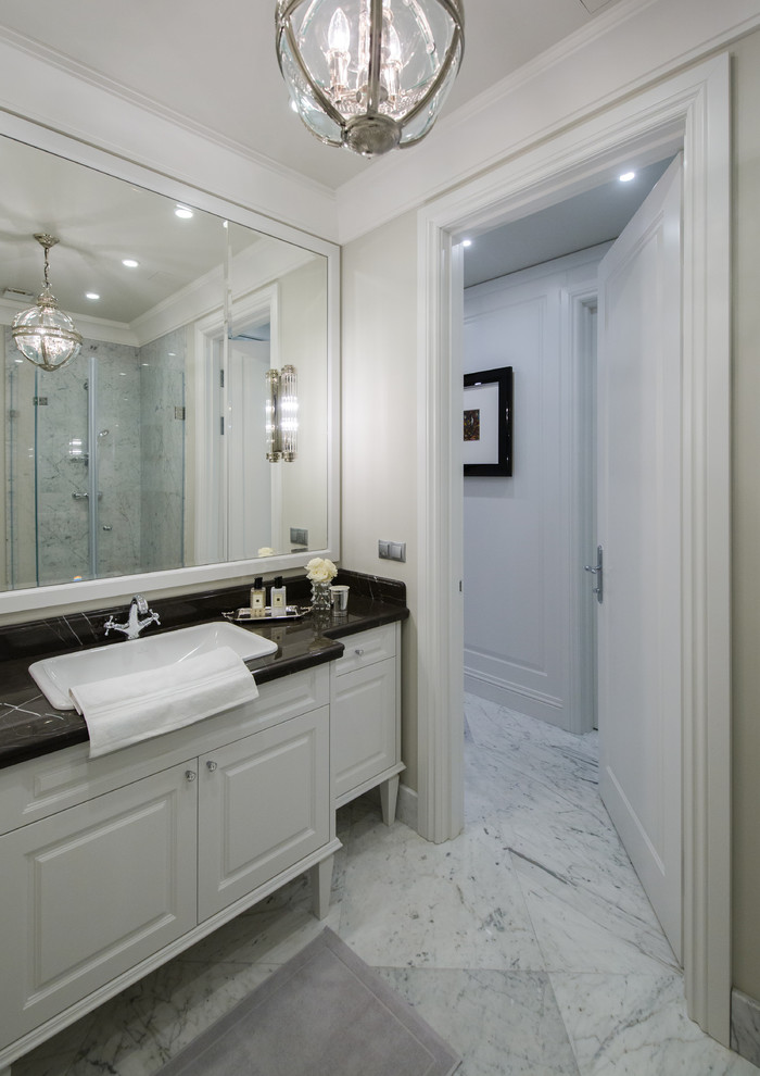 Klassisches Badezimmer mit profilierten Schrankfronten, weißen Schränken, weißer Wandfarbe, Einbauwaschbecken, weißem Boden und schwarzer Waschtischplatte in Moskau