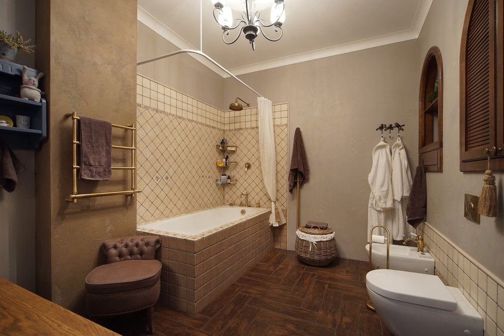 Idéer för ett stort lantligt gul en-suite badrum, med en dusch/badkar-kombination, en vägghängd toalettstol, beige kakel, porslinskakel, klinkergolv i porslin, luckor med lamellpanel, bruna skåp, ett undermonterat badkar, beige väggar, träbänkskiva och brunt golv