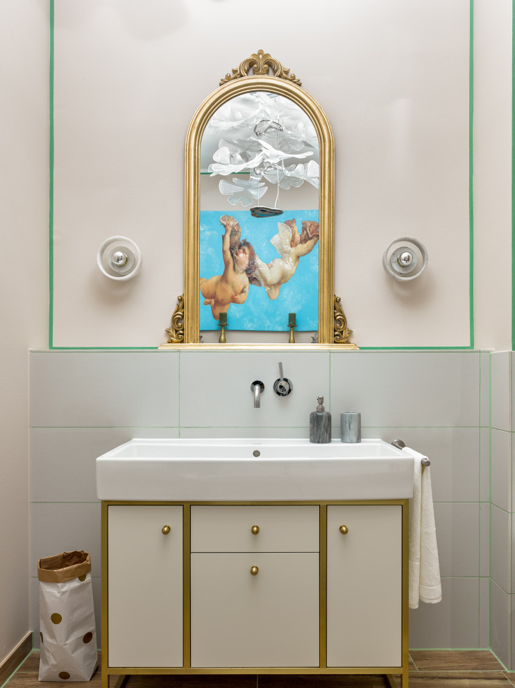 Modernes Badezimmer mit flächenbündigen Schrankfronten, weißen Schränken, grauen Fliesen, integriertem Waschbecken, braunem Boden, Einzelwaschbecken und freistehendem Waschtisch in Sonstige