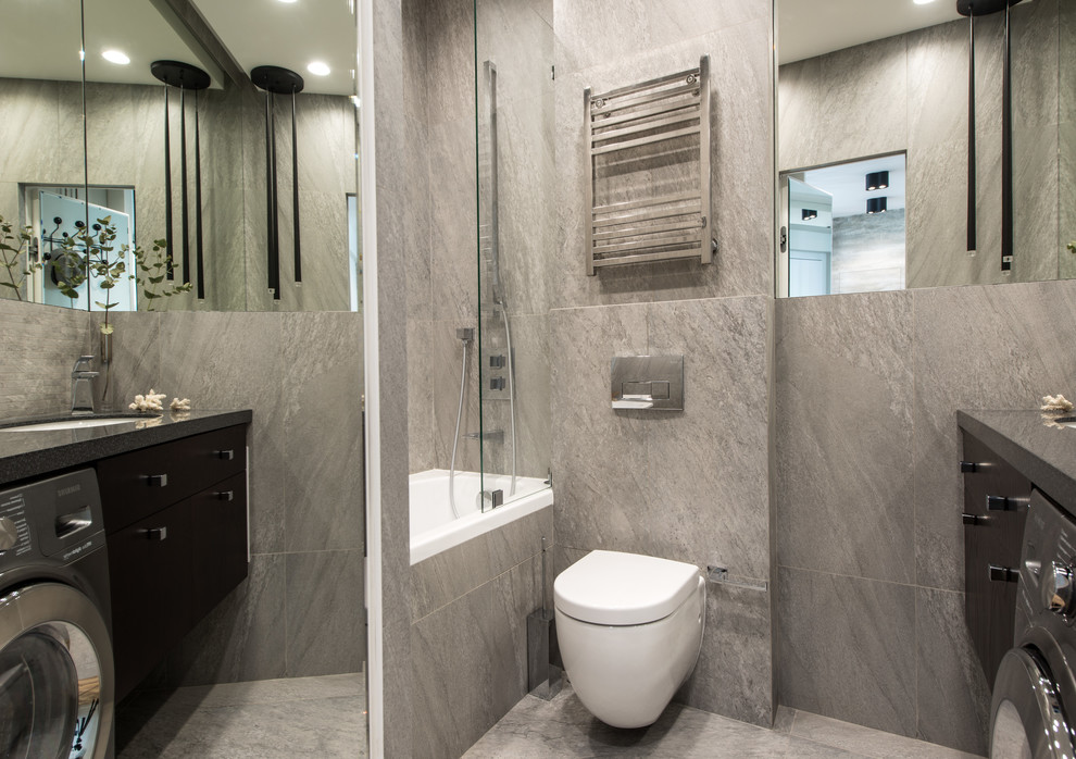 Foto de cuarto de baño principal actual con bañera empotrada, sanitario de pared y suelo gris