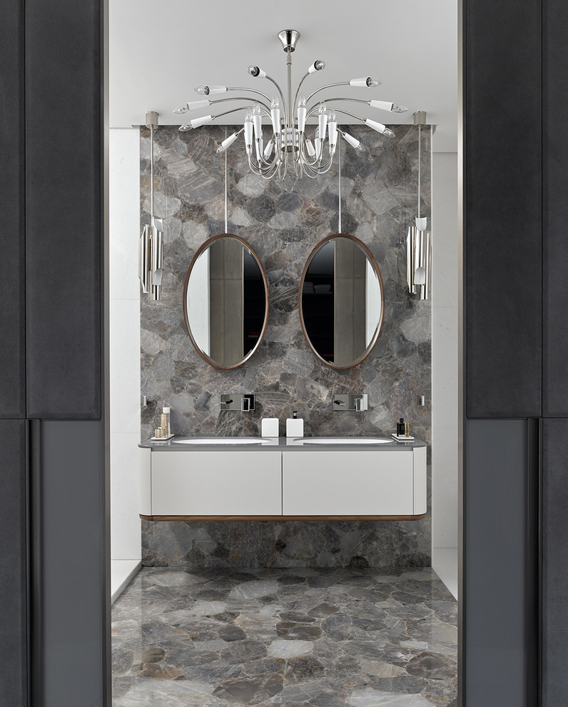 Cette image montre une salle de bain design avec un placard à porte plane, des portes de placard blanches, un lavabo encastré et un sol gris.