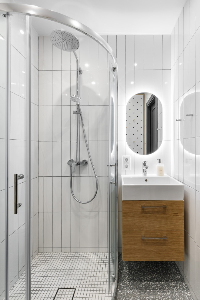 Minimalistisk inredning av ett badrum med dusch, med släta luckor, skåp i mellenmörkt trä, en hörndusch, terrazzogolv, grått golv och dusch med skjutdörr