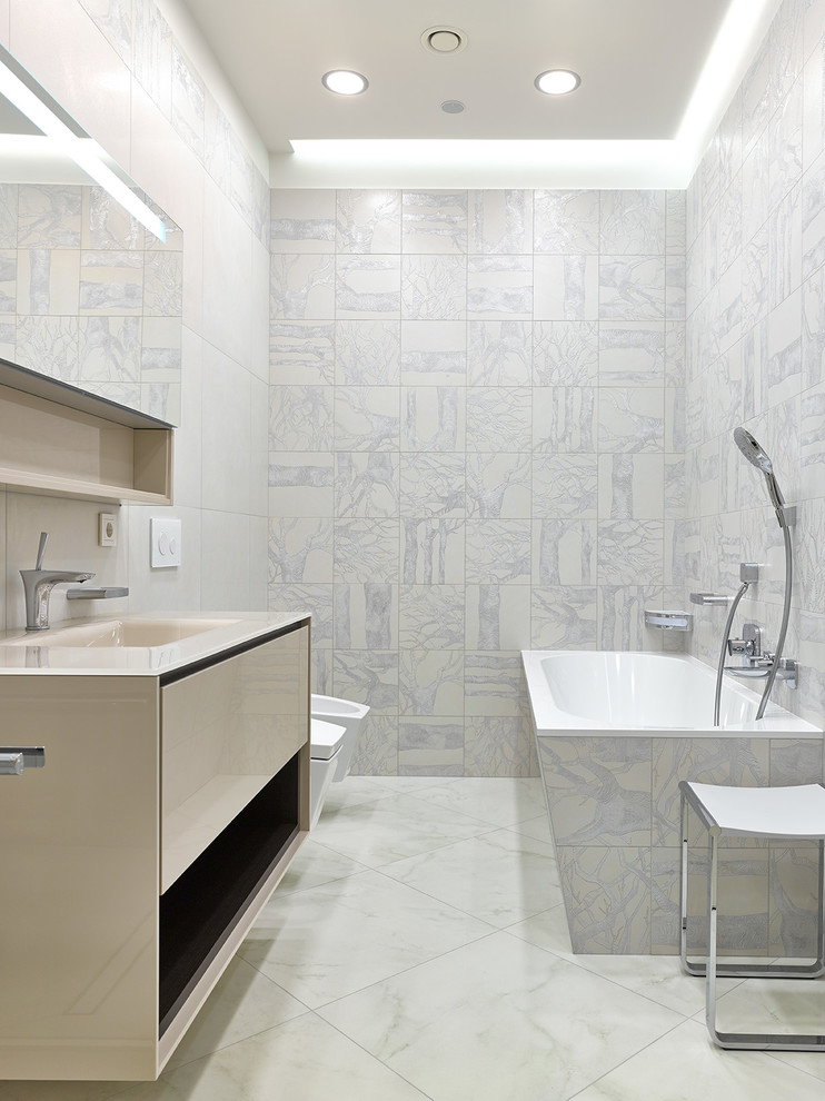 Idée de décoration pour une salle de bain principale design avec un placard à porte plane, des portes de placard beiges, WC suspendus, un lavabo intégré et un sol blanc.