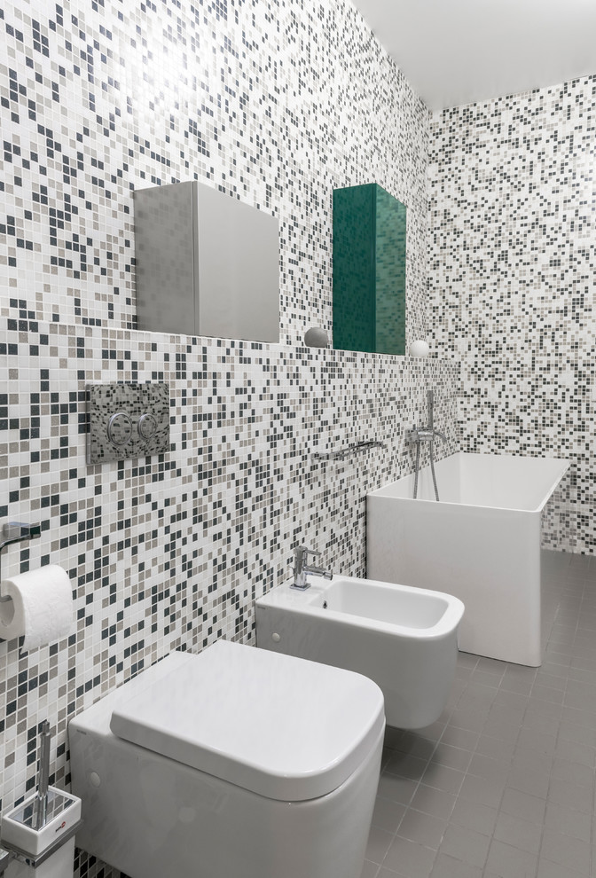 Inspiration för mellanstora moderna grönt en-suite badrum, med släta luckor, gröna skåp, ett fristående badkar, en vägghängd toalettstol, grå kakel, mosaik, grå väggar, cementgolv, ett fristående handfat, laminatbänkskiva och grått golv